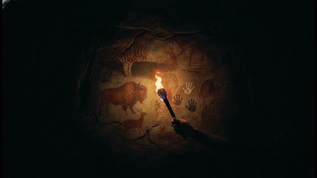 Uma tocha acesa ilumina a parede pintada da caverna